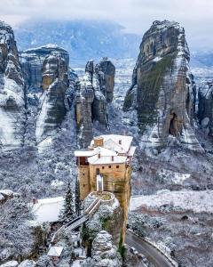 een gebouw aan de kant van een berg in de sneeuw bij Kalian Meteora in Kalabaka