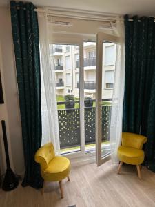 Zimmer mit zwei gelben Stühlen und einem Fenster in der Unterkunft Appartement avec vue sur jardin Paris-Disney-Parking privé 'PKN MEAUX' in Meaux