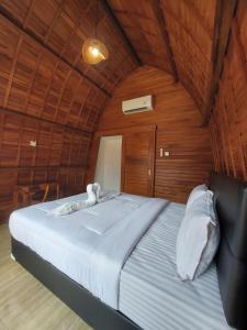 a large bed in a room with wooden walls at Les Chalets Pecatu in Uluwatu