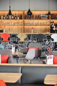 a restaurant with a black and white wall with chairs and tables at ibis Dinant Centre in Dinant