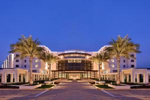 un edificio con palmeras delante en JW Marriott Hotel Muscat, en Mascate