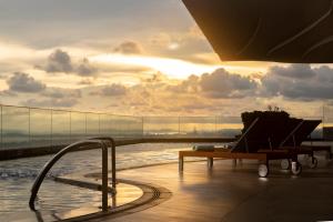 una piscina con panchina e una vasca idromassaggio in un edificio di Holiday Inn & Suites Rayong City Centre, an IHG Hotel a Rayong