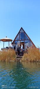 a house on the shore of a body of water at Uros Waliski Lodge in Puno