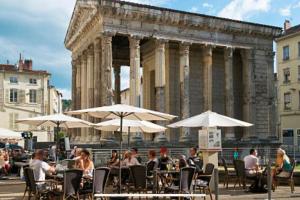 personnes assises à des tables avec des parasols devant un bâtiment dans l'établissement Appartement Vignes Vienne nord, à Vienne