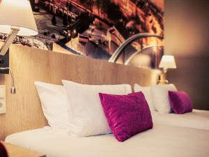 a bed with purple and white pillows in a hotel room at Mercure Lublin Centrum in Lublin