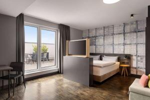 Vienna House Easy by Wyndham Bremen City Apartments في بريمين: غرفة نوم مع سرير وبلكونة مع طاولة