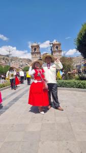 a man and woman in traditional dress standing on a street at Uros Waliski Lodge in Puno