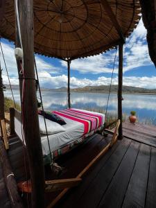 a bed on a porch with a view of the water at Uros Waliski Lodge in Puno