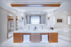 a bathroom with two sinks and a mirror and a tub at Sheraton Changsha Hotel in Changsha