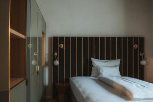 Arthotel Lasserhaus - adults only في Brixen: غرفة نوم مع سرير مع اللوح الأمامي المخطط