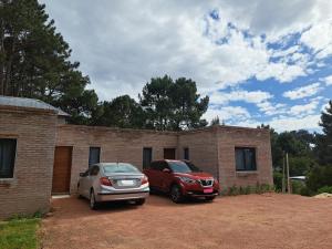 twee auto's geparkeerd voor een stenen huis bij NEco apartamentos Naturistas Nudistas Parejas o mujeres solas in Punta del Este