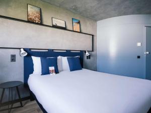 um quarto com uma grande cama branca com almofadas azuis em Ibis Barcelona Castelldefels em Castelldefels