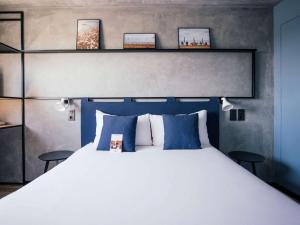 um quarto com uma grande cama branca com almofadas azuis em Ibis Barcelona Castelldefels em Castelldefels