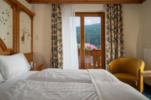 - une chambre avec un lit, une fenêtre et une chaise dans l'établissement Hotel Gianna, à Madonna di Campiglio