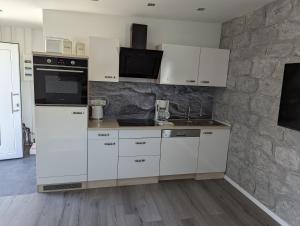 a kitchen with white cabinets and a stone wall at Pension Haus Leni am Schwanenteich in Mühlhausen