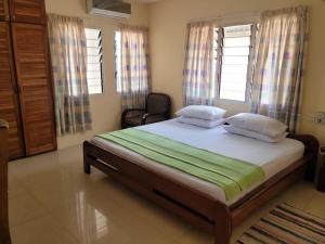 1 dormitorio con 1 cama y 2 ventanas en Loreto Palm Villa, en Cape Coast