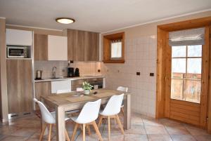 a kitchen with a wooden table and white chairs at Appartamento Trela 2 in Livigno