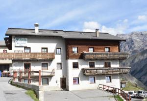 a large white building with wooden balconies and mountains at Appartamento Trela 2 in Livigno