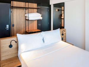 a bedroom with a bed with white sheets and white pillows at ibis Styles Maceió Pajuçara in Maceió