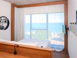 a bedroom with a bed and a large window at ibis Styles Maceió Pajuçara in Maceió