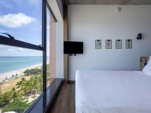 a bedroom with a bed and a view of the beach at ibis Styles Maceió Pajuçara in Maceió