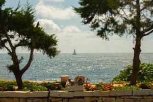 un velero en el agua con un muro de piedra y árboles en TheLuxuryVillas, en Preveza