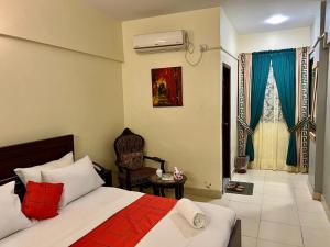 a bedroom with a bed and a chair in a room at Hotel Rooms DHA in Karachi