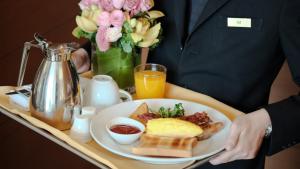 a person holding a tray with a plate of breakfast food at Hotel Rooms DHA in Karachi