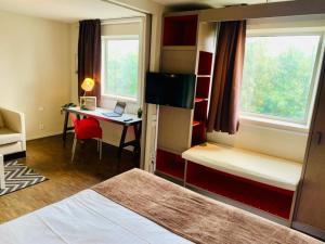 Zimmer mit einem Bett und einem Schreibtisch mit einem Laptop in der Unterkunft Standing Hotel Suites by Actisource in Roissy-en-France