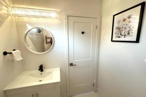 bagno bianco con lavandino e specchio di Exquisite, bright & modern condo. a Niagara Falls