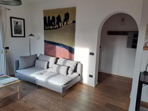 a white couch in a living room with a painting on the wall at Aosta Stunning Panoramic Views From Modern Two Bedroom Apartment in Aosta