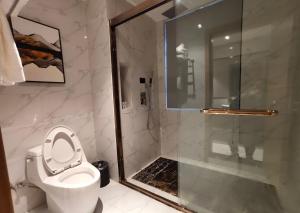 ein Bad mit einer Dusche, einem WC und einer Glastür in der Unterkunft Zhangjiajie Virgo Boutique Hotel in Zhangjiajie