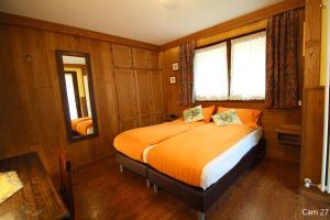 um quarto com uma cama com lençóis laranja e uma janela em Hotel Meynet em Breuil-Cervinia