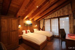 um quarto com 2 camas num quarto com paredes de madeira em Hotel Meynet em Breuil-Cervinia