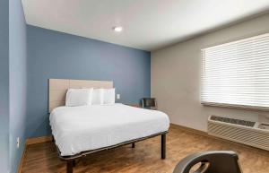 een slaapkamer met een bed met een blauwe muur bij Extended Stay America Select Suites - Fayetteville - I-49 in Fayetteville