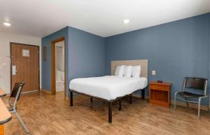 een blauwe slaapkamer met een bed en een stoel bij Extended Stay America Select Suites - Fayetteville - I-49 in Fayetteville