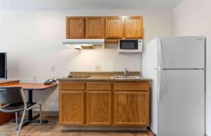 een keuken met houten kasten en een witte koelkast bij Extended Stay America Select Suites - Fayetteville - I-49 in Fayetteville