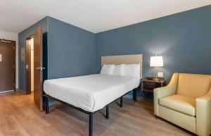 - une chambre avec un lit et une chaise dans l'établissement Extended Stay America Suites - St Paul - Woodbury, à Woodbury