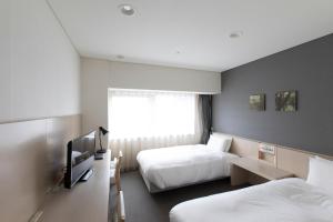 een hotelkamer met 2 bedden en een televisie bij X wave Funabashi in Funabashi