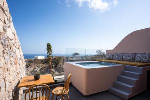 une terrasse avec un bain à remous, une table et des chaises dans l'établissement Perla Nera Suites, à Fira