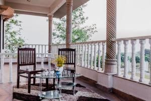 een veranda met 2 stoelen en een glazen tafel bij Silver Galaxy Resort in Panchgani