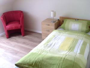 een slaapkamer met een groen bed en een rode stoel bij Ferienwohnung am Waldrand in Schmallenberg