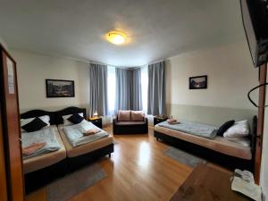 a living room with two beds and a chair at Alcorso Pension in Banská Bystrica