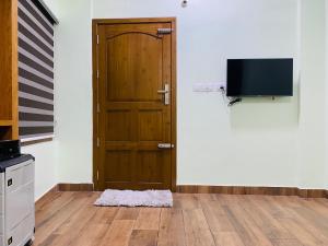 een deur in een kamer met een televisie en een vloer bij AL-Kabeer Lavender budget rooms in Trivandrum