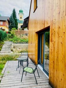 une terrasse en bois avec une table et des chaises. dans l'établissement Harrachov 702, à Harrachov