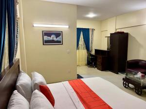 a bedroom with a bed and a desk in a room at Hotel Rooms DHA in Karachi