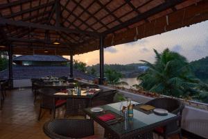 ein Restaurant mit Tischen und Stühlen und Flussblick in der Unterkunft The Raviz Kadavu, Kozhikode in Kozhikode