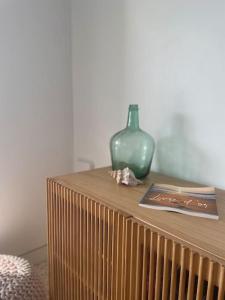 a wooden table with a green vase on top of it at Can Estrellas, appartement d'exception sur la mer in Roses