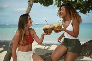 deux femmes assises sur la plage et tenant des noix de coco dans l'établissement Azul Beach Resort Negril, Gourmet All Inclusive by Karisma, à Negril