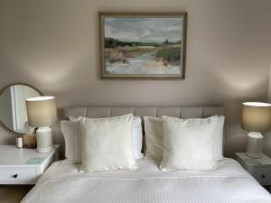 Castlecroft Bed and Breakfast في ستيرلينغ: سرير ومخدات بيضاء وصورة على الحائط